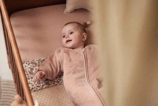 bébé dans un lit avec une gigoteuse rose à fermeture