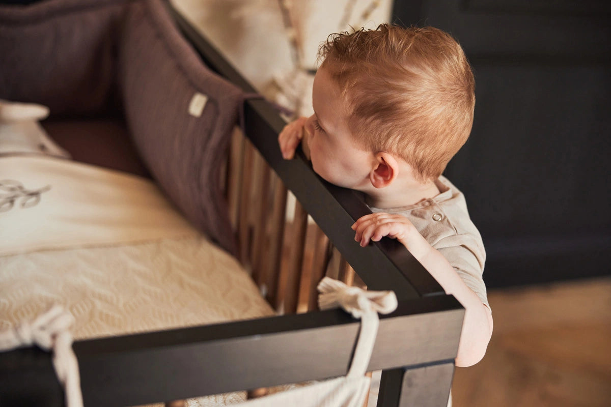 Bébé qui regarde dans son lit avec un tour de lit 